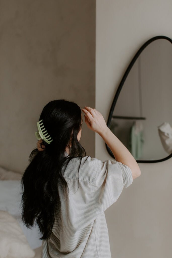 Woman with straight hair using wide-tooth comb showing proper detangling technique for hair types that distribute sebum easily