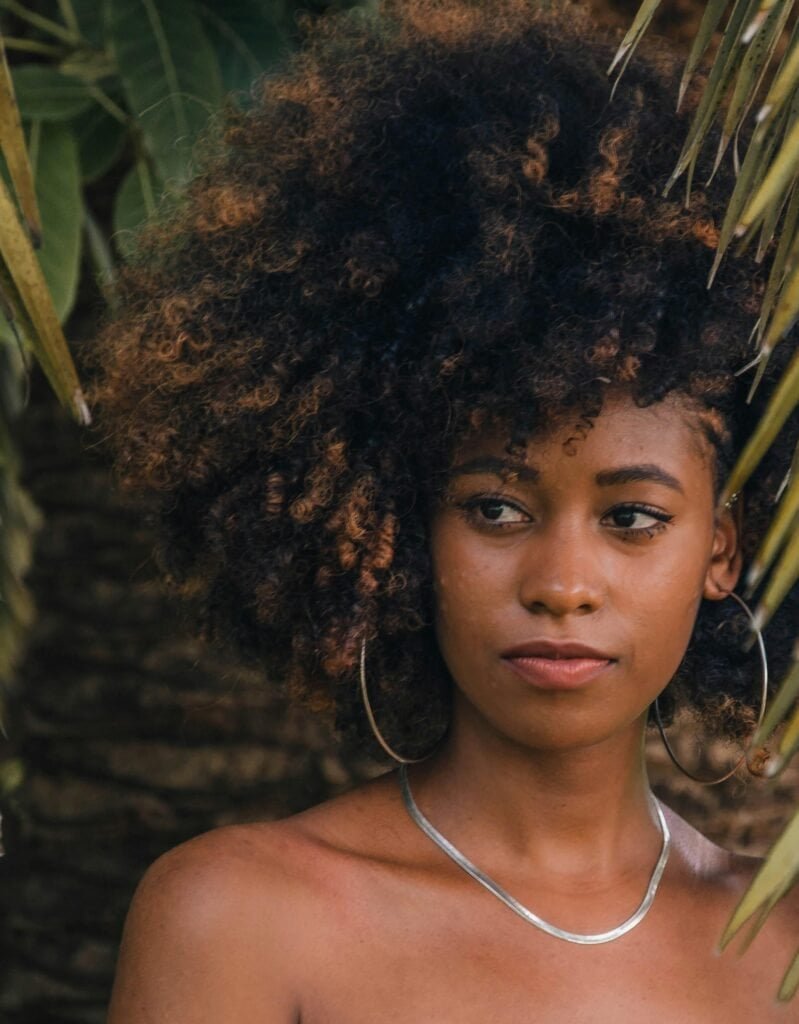 Black woman with healthy natural Afro-textured hair exemplifying results of weekly washing routine and proper moisture maintenance