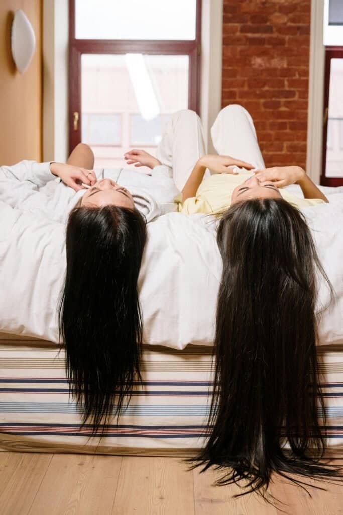 Women with long straight Asian hair displaying healthy shine and smoothness achieved through frequent washing every 1-3 days routine
