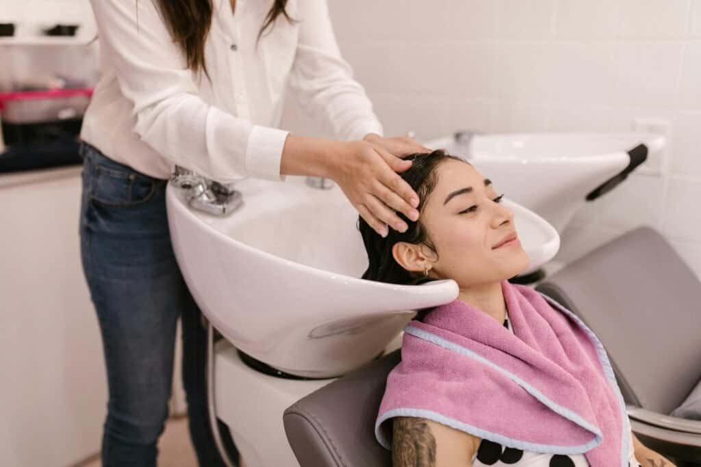 Hair stylist performing scalp massage during professional wash showing correct technique focusing on scalp not just hair