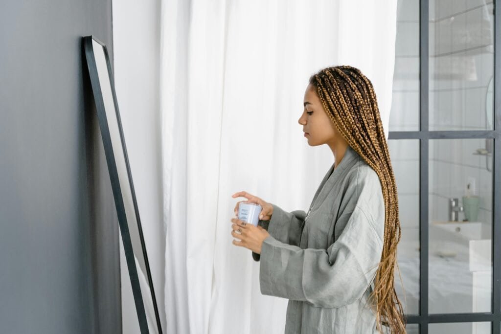 Woman with box braid protective style preparing scalp care routine illustrating 2-week maximum washing requirement for braided hair health