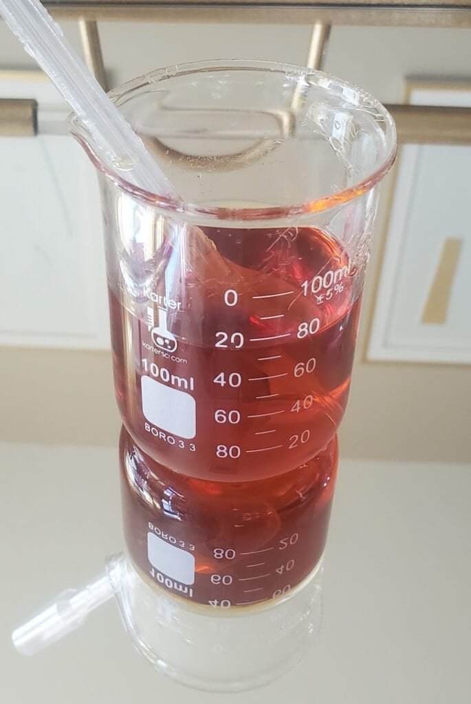 Apple cider vinegar concentrate in glass beaker - DIY natural ingredient preparation for pH-balancing dandruff treatment
