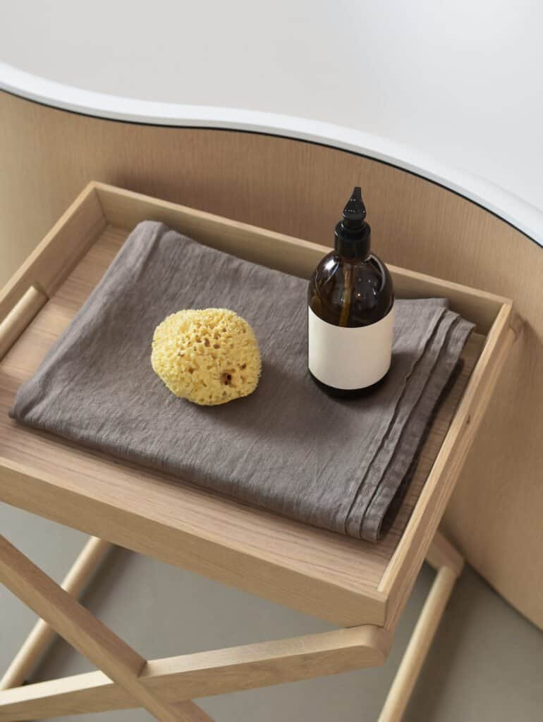 Amber glass dropper bottle and natural sponge arranged for scalp wellness routine and gentle hair care