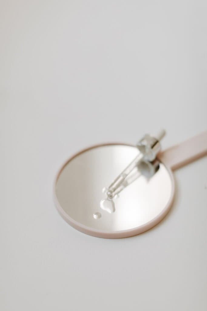 Glass pipette measuring scalp care oil drops into white bowl for DIY natural scalp treatment recipe