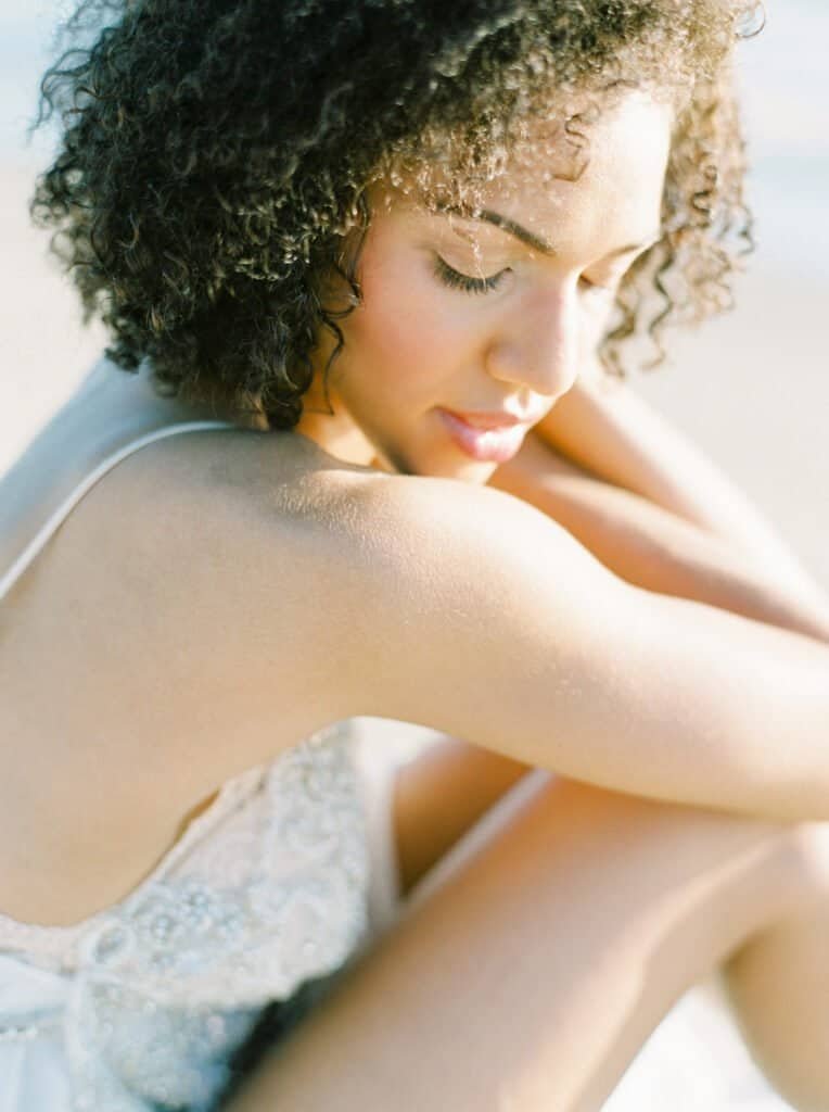 Woman with lustrous natural curly hair in tranquil moment, showing results of customized scalp routine for textured hair