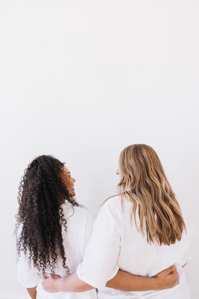 Two women with healthy, flake-free hair showing successful results from natural dandruff treatment - curly and straight hair types