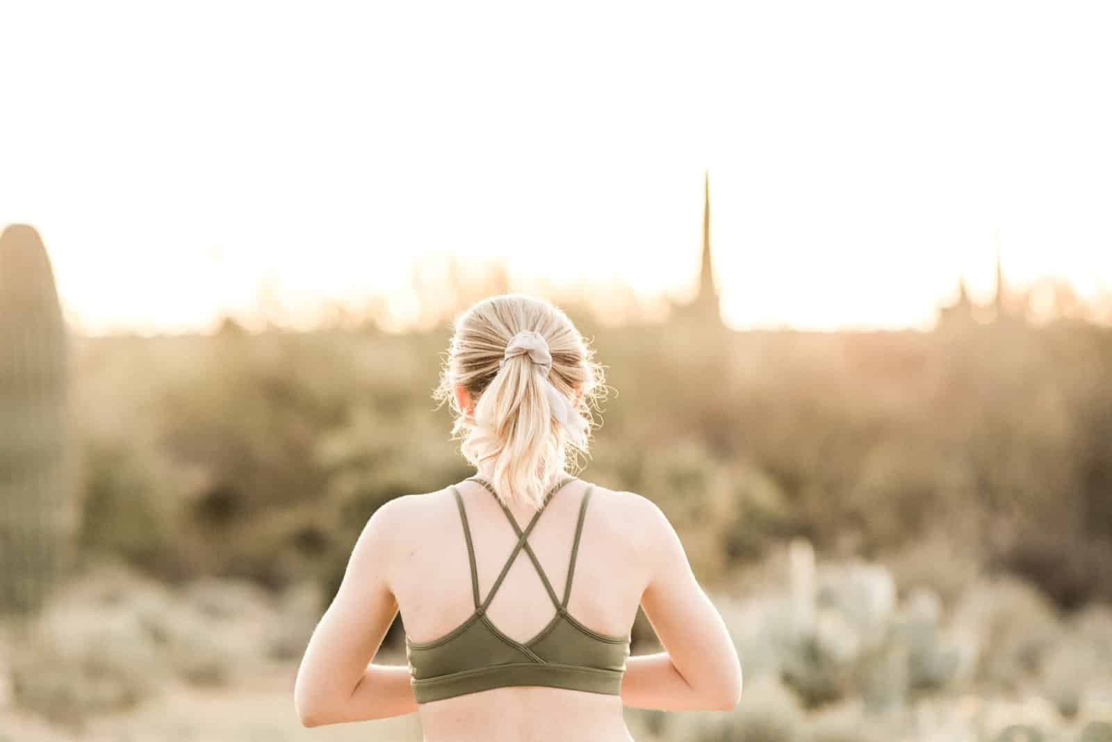 Woman with exposed skin standing outdoors during sunset, highlighting the importance of natural sun protection for preventing skin damage and cancer while enjoying nature