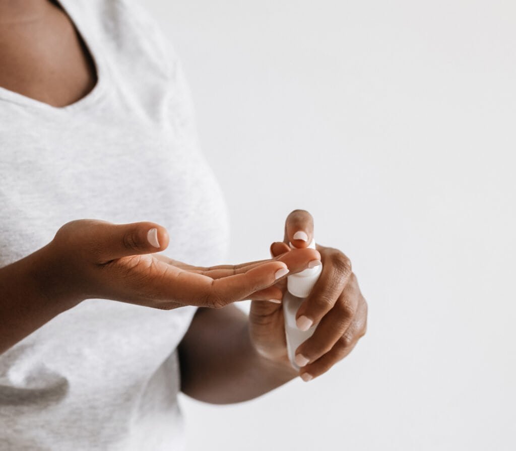 Close-up of hands applying a white cream or serum, demonstrating the proper application technique for morning skincare routine. This image illustrates the gentle, measured approach to applying natural hyperpigmentation treatments discussed in our step-by-step morning protocol, emphasizing the importance of using the right amount of product and proper application methods for maximum effectiveness.