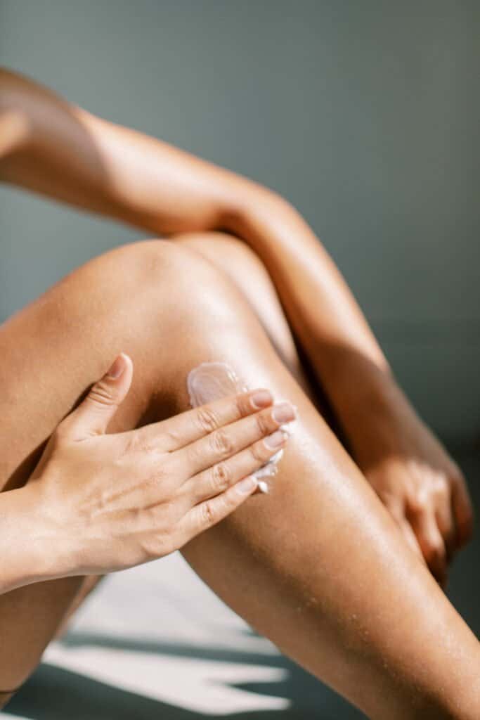 Person applying sunscreen to their knee with fingers, showing the proper amount needed for effective protection - relevant to our article 'The Truth About Sunscreen: 8 Facts The Industry Doesn't Want You To Know' which discusses sunscreen application effectiveness