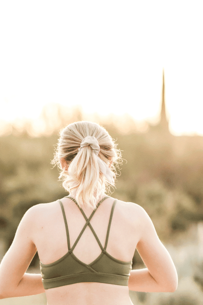 Fair-skinned blonde woman with back exposed to warm sunlight outdoors, illustrating the need for holistic sun protection beyond sunscreen to shield skin from UV-induced free radical damage and photoaging