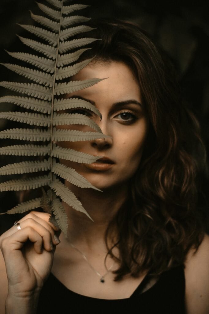 Artistic portrait of woman holding dried fern frond illustrating natural skincare and Polypodium leucotomos benefits