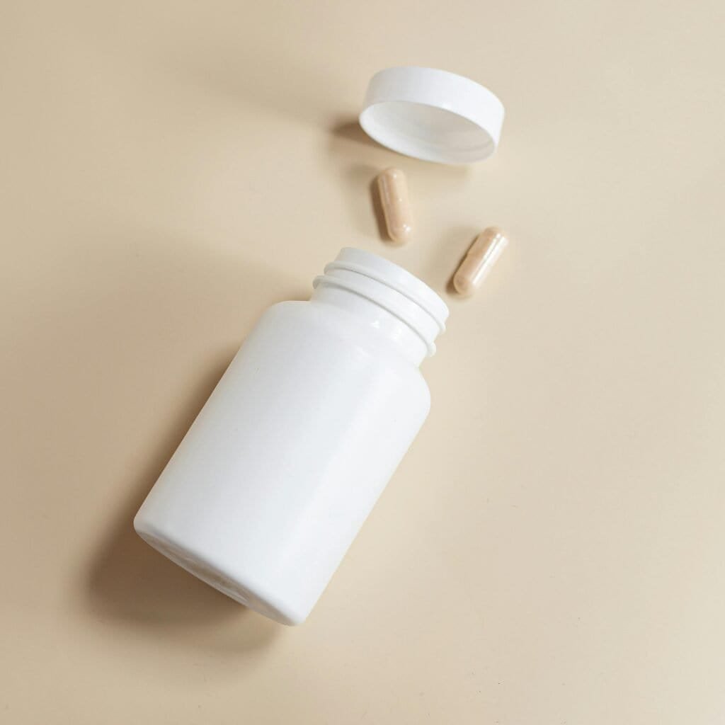 White supplement bottle with Polypodium leucotomos capsules on beige background