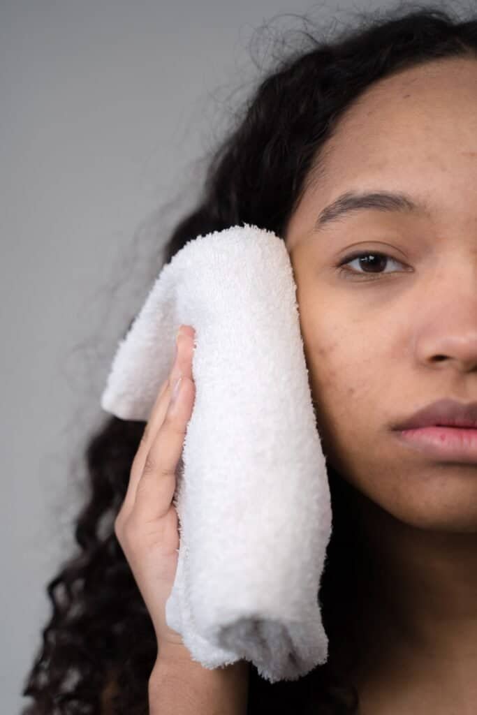 Woman gently patting her face dry with a towel after cleansing